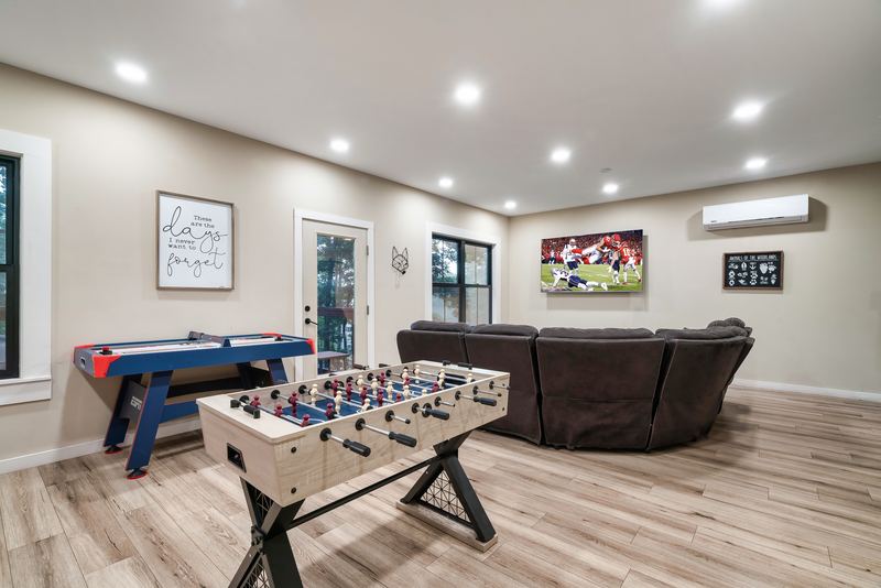 Game room with air hockey and foosball tables, a sectional and a wall-mounted TV