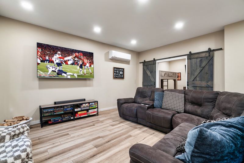 Big-screen TV, dark sectional and a shelf of board games in the game room