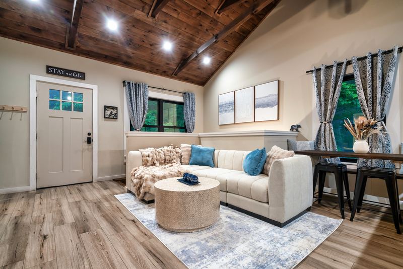 Living room with a cream sectional and round coffee table under a vaulted wood ceiling